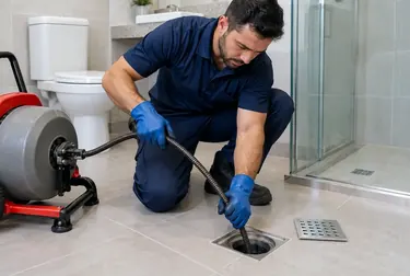 Profissional trabalhando em desentupimento de ralo com equipamentos específicos.